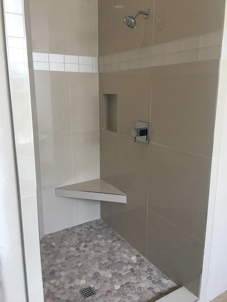 Tiled walk-in shower with a corner bench and pebble floor